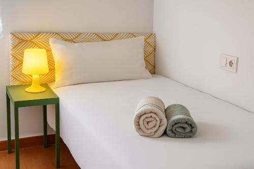 a white bed with towels on it next to a lamp at Sol y Olivos Apartamentos de 1 o 2 dormitorios en el centro de Jaén in Jaén