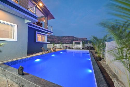 a blue swimming pool in front of a house at ll EMPYREAN STAY ll MIRAGE CHALET ll 4BHK ll AC ll LARGEST POOL ll in Lonavala