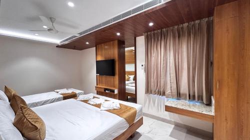 a hotel room with two beds and a television at The Paradise Platinum in Kanchipuram