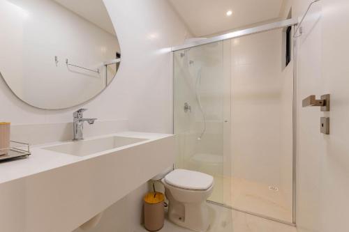 a bathroom with a toilet and a sink and a mirror at Belissimo apto alto padrão a 50 mts da praia in Bombas