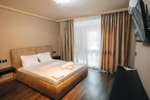a bedroom with a bed and a large window at Noon Central Hotel in Tirana