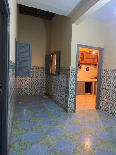 a room with a tile floor and a kitchen at Tayrt Hostel in Mirleft