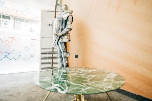 a statue of a man standing next to a glass table at Noon Central Hotel in Tirana