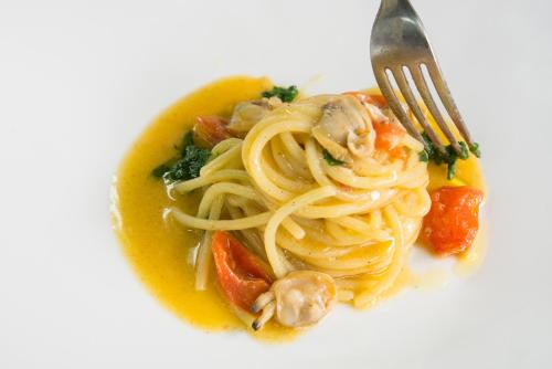 a plate of pasta with shrimp and vegetables with a fork at Albergo Diffuso Bacco Furore in Furore