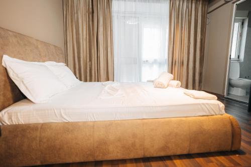 a large white bed in a room with a window at Noon Central Hotel in Tirana