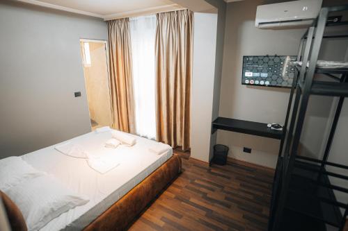 a bedroom with a white bed and a window at Noon Central Hotel in Tirana