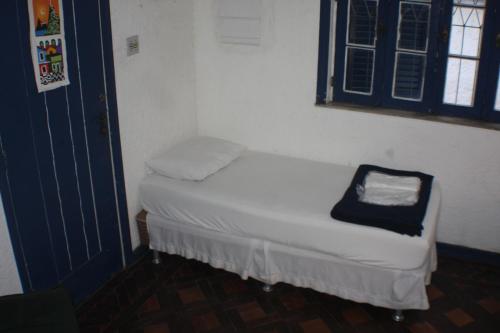 a small white bed in a room with a window at Farfalla Guest House in Rio de Janeiro