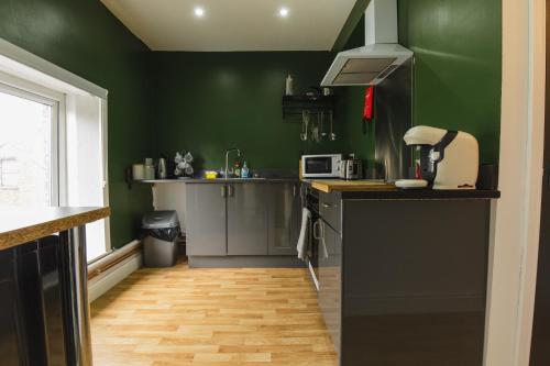 a kitchen with green walls and a wooden floor at Windsor Stays 2 in Liverpool