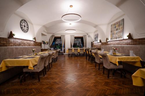 a dining room with tables and chairs and a clock at Hotel Arkada in Levoča