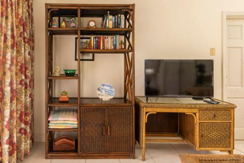 a living room with a television and a wooden entertainment center at Caribbliss Suites in Lowlands
