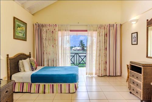 a bedroom with a bed and a large window at Caribbliss Suites in Lowlands