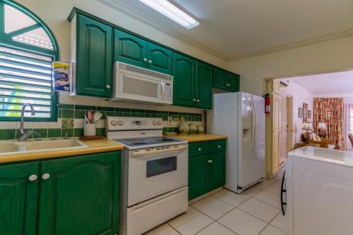 a green kitchen with white appliances and green cabinets at Caribbliss Suites in Lowlands