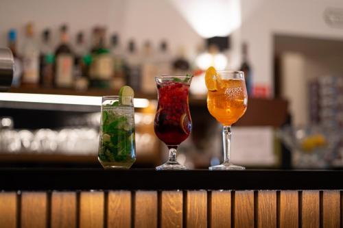 three cocktails sitting on a counter in a bar at Hotel Arkada in Levoča