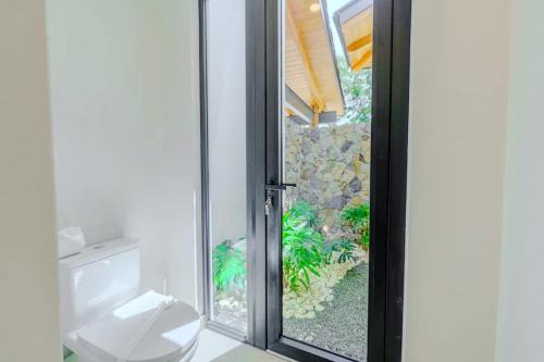 a bathroom with a toilet and a sliding glass door at Casa Nimbu - Hacienda Pinilla in Playa Avellana