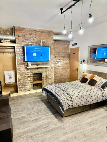 a bedroom with a brick wall with a bed and a tv at Luxury Industrial Studio Leeds Near Brudenell social club & Headingley Stadium in Headingley