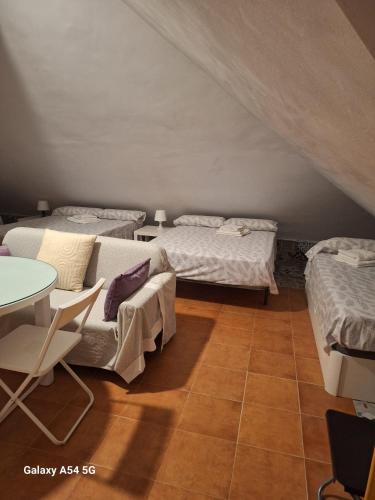 a room with three beds and a table and a table at Apartamento en Buhardilla de Casa Andaluza in Bollullos de la Mitación