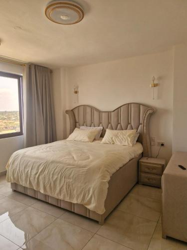 a bedroom with a large bed with a large headboard at Almasi Suites at Sandyshore Beach Resort in Kikambala