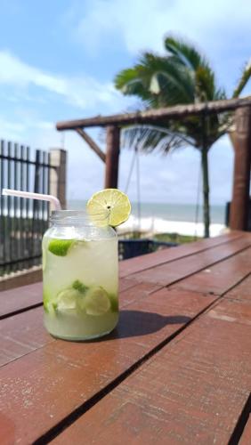 uma bebida sentada numa mesa de madeira com uma fatia de cal em Quarto frente mar com sacada! em Barra Velha