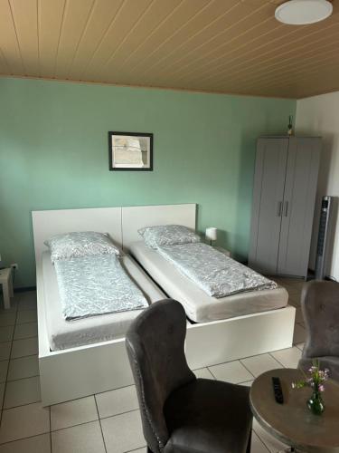 two beds in a room with a table and chairs at Pension Zum Paradies in Harthausen