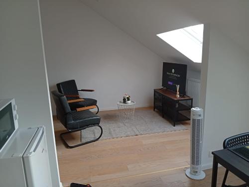 un salon avec deux chaises et une télévision dans l'établissement studio supérieur, à Marcinelle