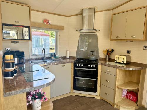 a kitchen with a stove and a sink at Private Hot Tub & Spacious Decking Area in Northumberland, Dog-Friendly, Free Golf Access in Swarland