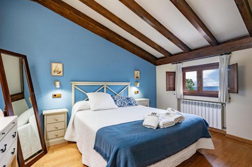 a bedroom with blue walls and a bed with towels on it at La Quintana de Somao, Casa de Arriba in Somado