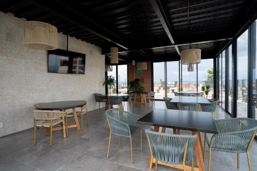 une salle à manger avec tables, chaises et fenêtres dans l'établissement Suite con Cama King y Queen, Wi-Fi Rápido y Amenidades Top, à Guadalajara