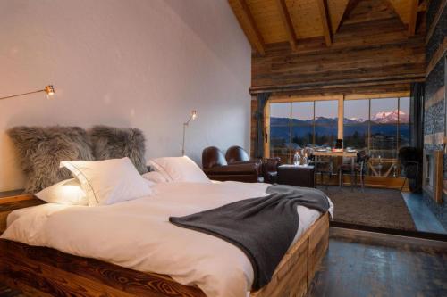 a bedroom with a large bed with a large window at Hostellerie du Pas de l'Ours "Relais et Châteaux" in Crans-Montana