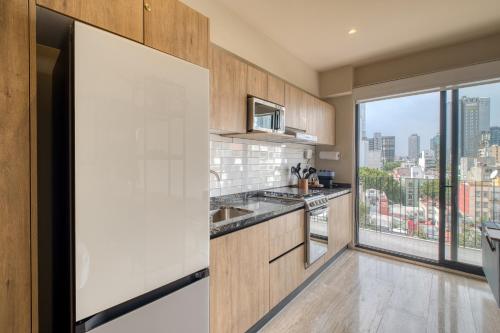 a kitchen with wooden cabinets and a large window at Myla Chapultepec in Mexico City