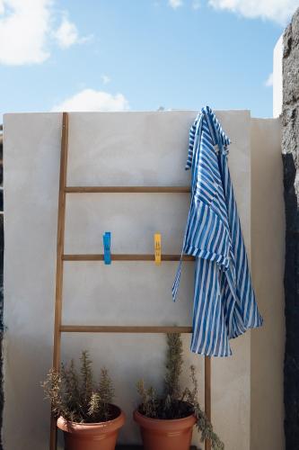a towel hanging on a wall next to potted plants at Athera Luxury Villas in Santorini
