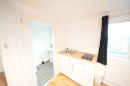a white kitchen with a sink and a window at Great Airport Sleep PRIVATE bathroom in all ROOMS in Harmondsworth