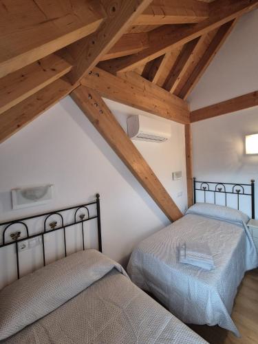 two beds in a room with wooden ceilings at NUEVO OCTUBRE 2025 Dúplex Sierra de Cazorla II in Arroyo Frio