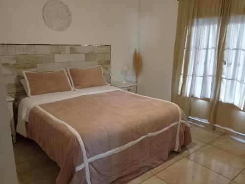 a bedroom with a large bed and two windows at Hospedaje El Ciruelo in Alta Gracia