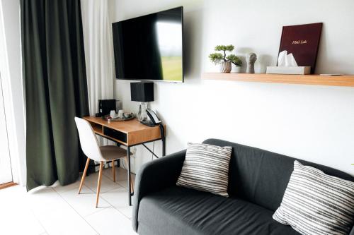 a living room with a couch and a desk with a television at Hotel Laki in Kirkjubæjarklaustur