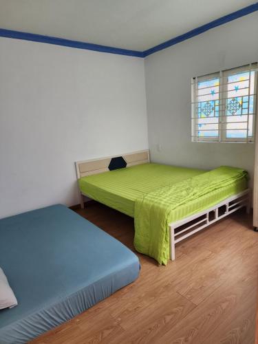 ホーチミン・シティにあるBinh Minh Homstayのベッドルーム1室(ベッド2台、緑のシーツ、窓付)