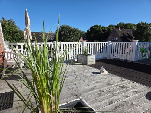 a cat sitting on a deck next to a white fence at Pension Zur Brandung in Büsum