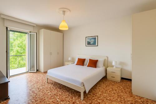 a bedroom with a white bed and a large window at Pietra Ligure Sea View Parking & Bike Box in Pietra Ligure