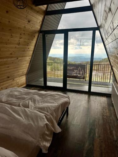 a bedroom with a bed and a large window at La Popasul Cerbului in Semenic