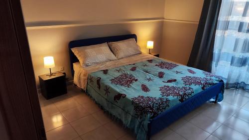 a bedroom with a bed with a blue comforter and two lamps at Casa Balcone sul Castello in Aci Castello