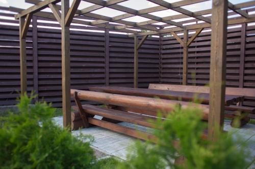 a wooden bench sitting under a wooden pergola at Fazenda in Sumy