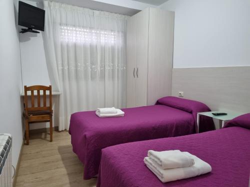 a room with two beds with purple sheets at Hostal O Patron in Santiago de Compostela
