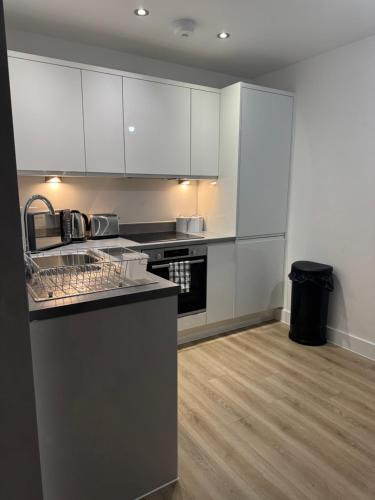 a kitchen with white cabinets and a counter top at Elegant 1 Bed Flat Near Stadium & Shops and free parking in Manchester
