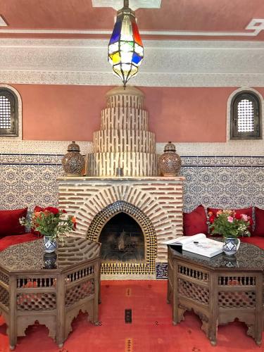 a living room with a fireplace with two tables at Riad Tasneem in Marrakech