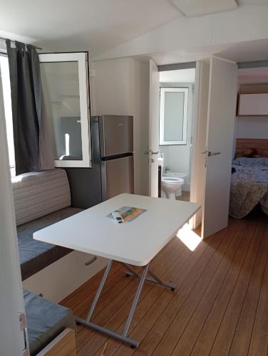 a living room with a white table and a kitchen at Casetta sul mare in Lido di Classe
