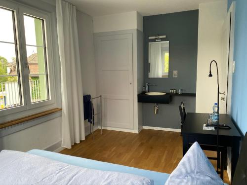 a bedroom with a bed and a bathroom with a sink at BnB Hopfengrün Langenthal in Langenthal