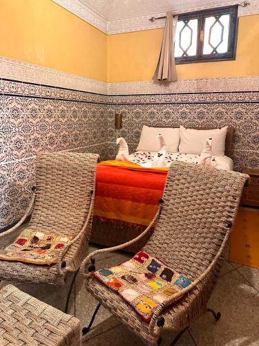a bedroom with a bed and two wicker chairs at Riad Tasneem in Marrakech