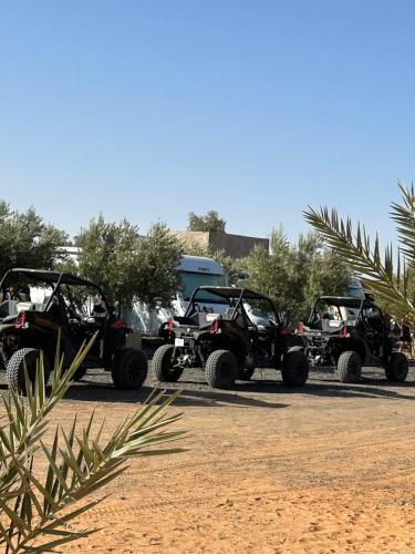 a group of four atvs parked in a parking lot at Hôtel Camping La Liberté in Merzouga