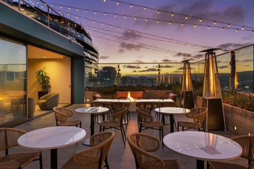 a patio with tables and chairs and a view of the city at AC Hotel by Marriott Beverly Hills in Los Angeles