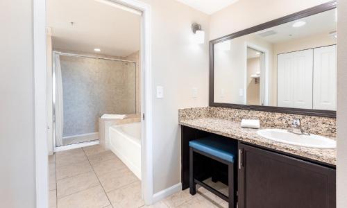 a bathroom with a sink and a mirror and a tub at Vacation Village Orlando, Celebration in Orlando