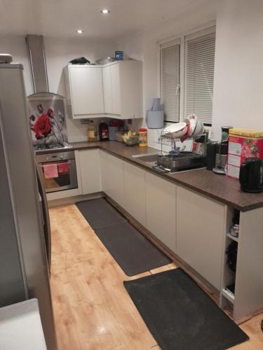a kitchen with white cabinets and a wooden floor at Cullen Sqaure in South Ockendon